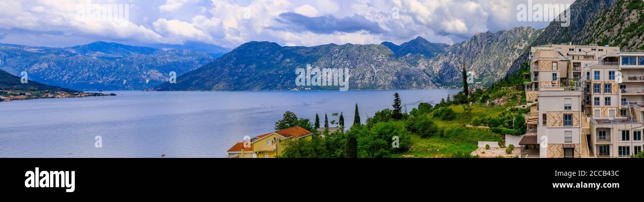 Luftaufnahme von Wohngebäuden entlang der Küste der Bucht von Kotor und Berge im Hintergrund im Sommer in Dobrota, Montenegro Stockfoto