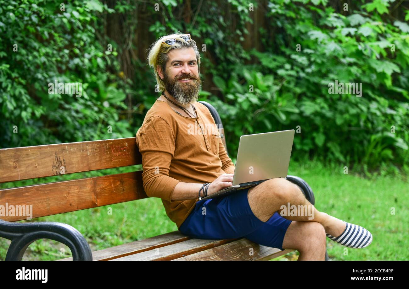 Business-Mann arbeiten im Freien mit Computer. Starten Sie Videokonferenzen. Kommunikation per Videoanruf. Geschäftsmann mit Laptop auf Bank im Park. Hübscher Mann, der am Laptop arbeitet. Mit modernen Technologien. Stockfoto