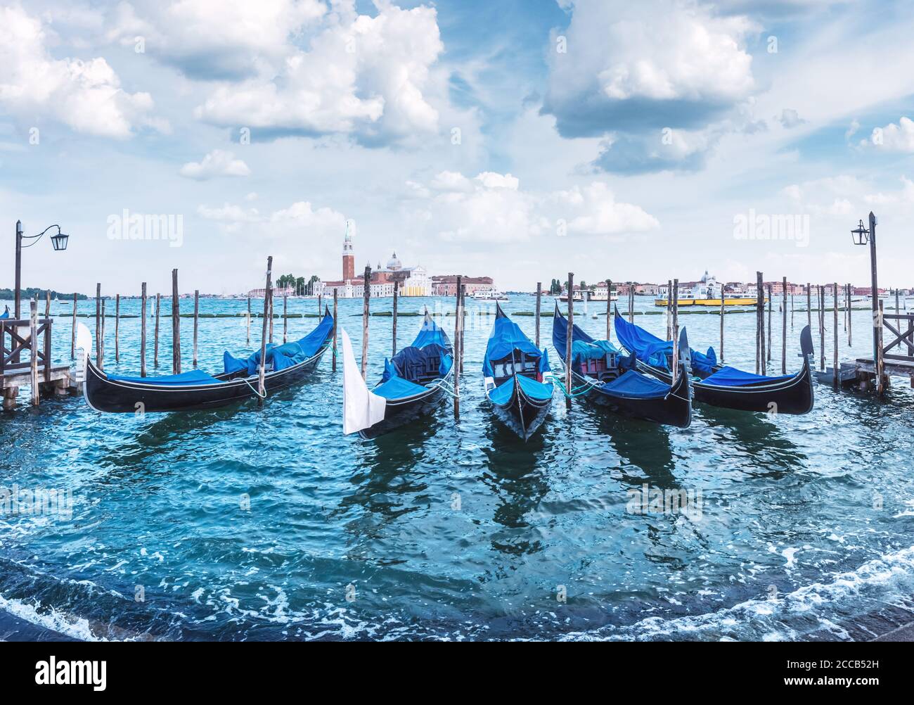 Bunte Landschaft mit klarem blauen Himmel auf dem markusplatz in Venedig. Eine Reihe von Gondeln, die am Pier der Stadt geparkt sind. Kirche San Giorgio Maggiore im Hintergrund, Italien, Europa Stockfoto
