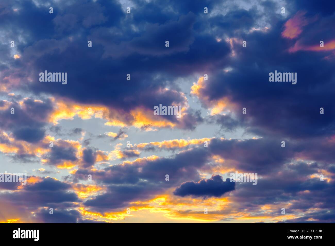 Ein sehr dramatischer Himmel voller Gelb, Blau und Orangen. Kontrastierende Wolken während des Sonnenuntergangs von der untergehenden Sonne beleuchtet. Hell gesättigt natürlich Stockfoto