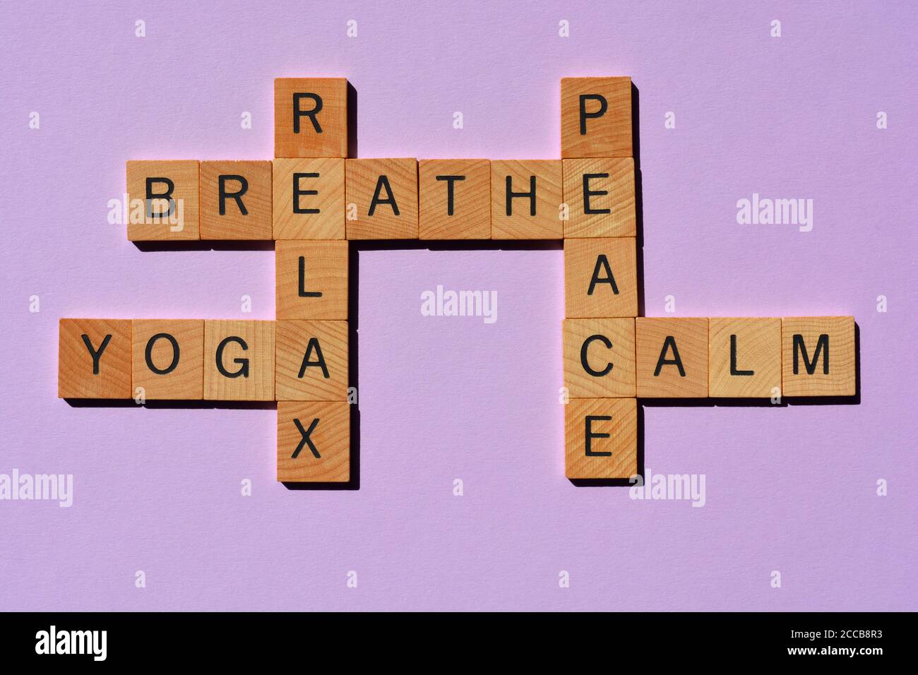 Yoga, Atmen, Entspannen, Frieden, Ruhe, Kreuzworträtsel in Holzbuchstaben in Kreuzworträtsel-Form isoliert auf violettem Hintergrund Stockfoto
