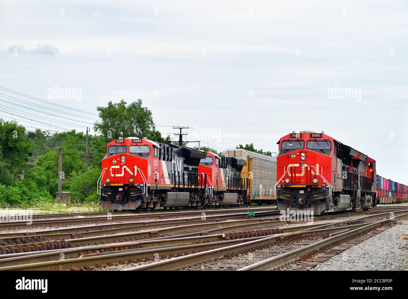 Homewood, Illinois, USA. Zwei kanadische nationale Lokomotiven, die positioniert werden, um einen ausgehenden Güterzug zu führen, passieren ein weiteres Paar Einheiten. Stockfoto