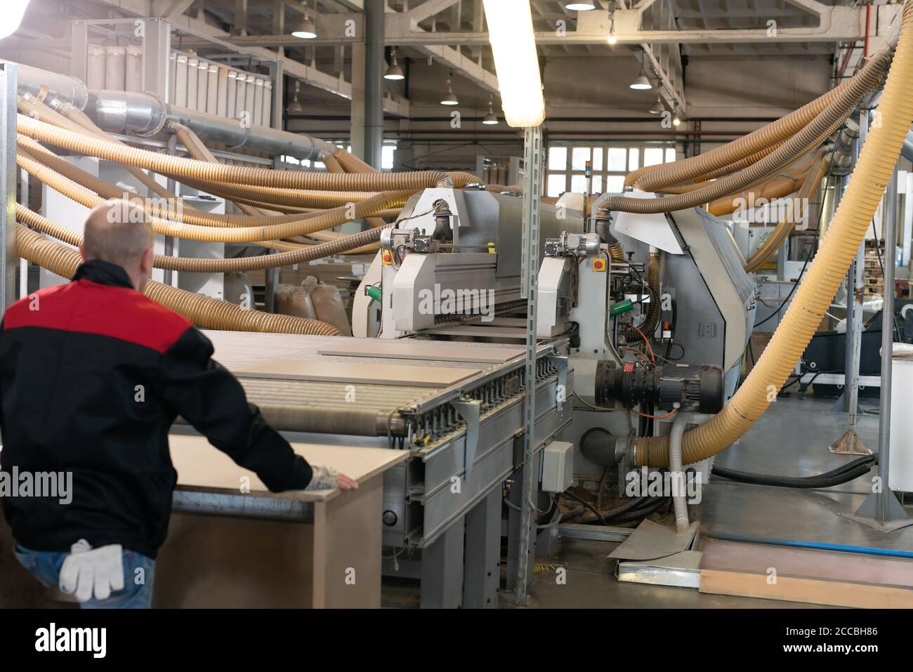 Anonymer Mann, der im Werk mit Spanplatten arbeitet Stockfoto