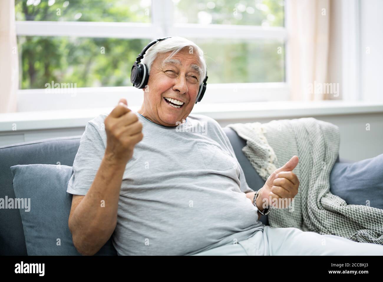 Lächelnd Ältere Senior Listening Musik Auf Kopfhörer Stockfoto