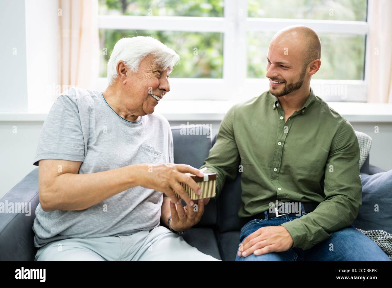 Seniorbürger, Der Ein Festgeschenk Im Pflegeheim Erhält Stockfoto