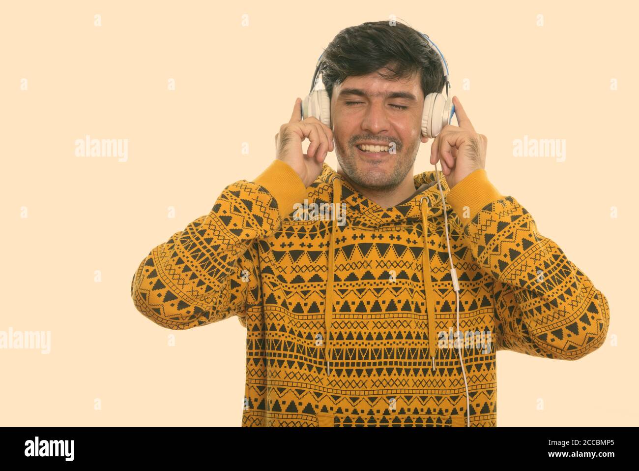 Junge glücklich Persischen Mann lächelnd, während Sie Kopfhörer und das Hören von Musik mit geschlossenen Augen Stockfoto