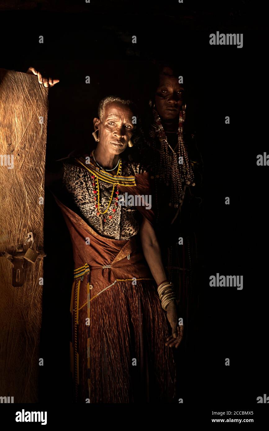 Afrikanische Frauen in einem Boma, beleuchtet durch das Licht der Tür. Stockfoto