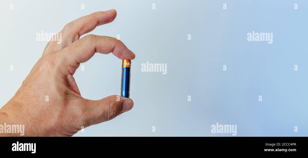 Hand des Mannes, der kleine AAA-Batterie zwischen Daumen und Zeigefinger hält. Platz kopieren Stockfoto
