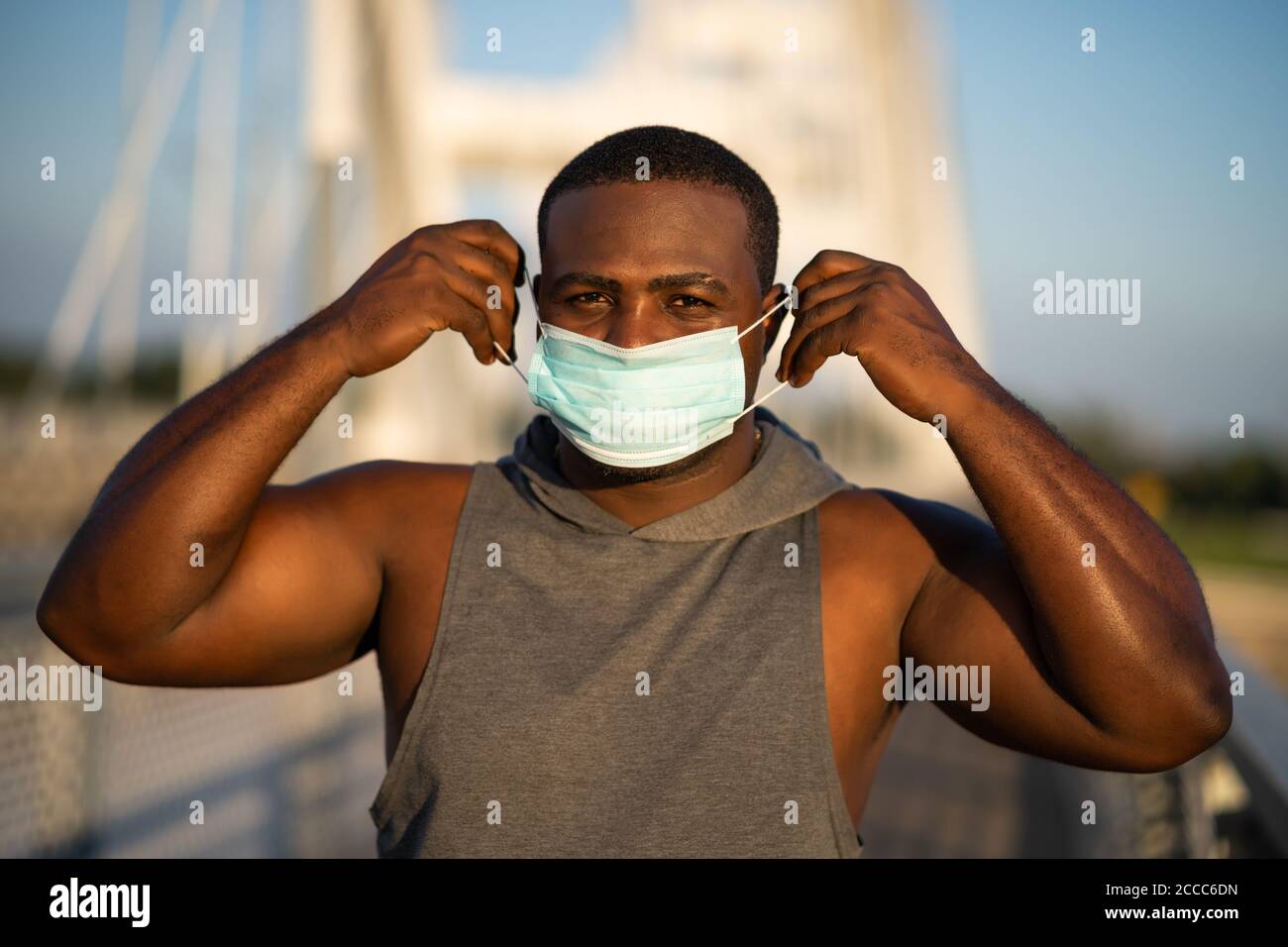 Der junge afroamerikanische Mann legt ihm vor dem Joggen eine Schutzmaske ins Gesicht. Corona Virus Pandemie verantwortliches Verhalten. Stockfoto