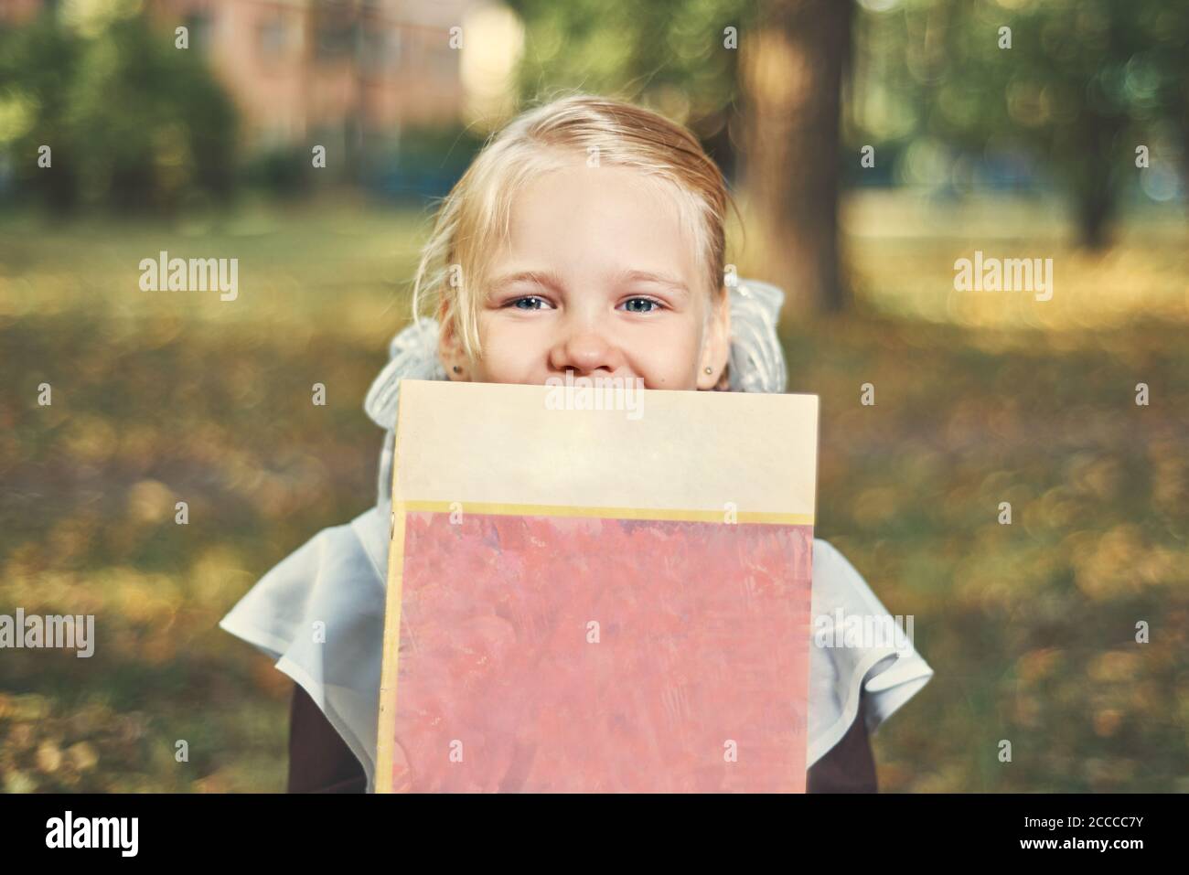 Porträt eines glücklichen Kindes, das sich hinter einem Buch versteckt. Stockfoto