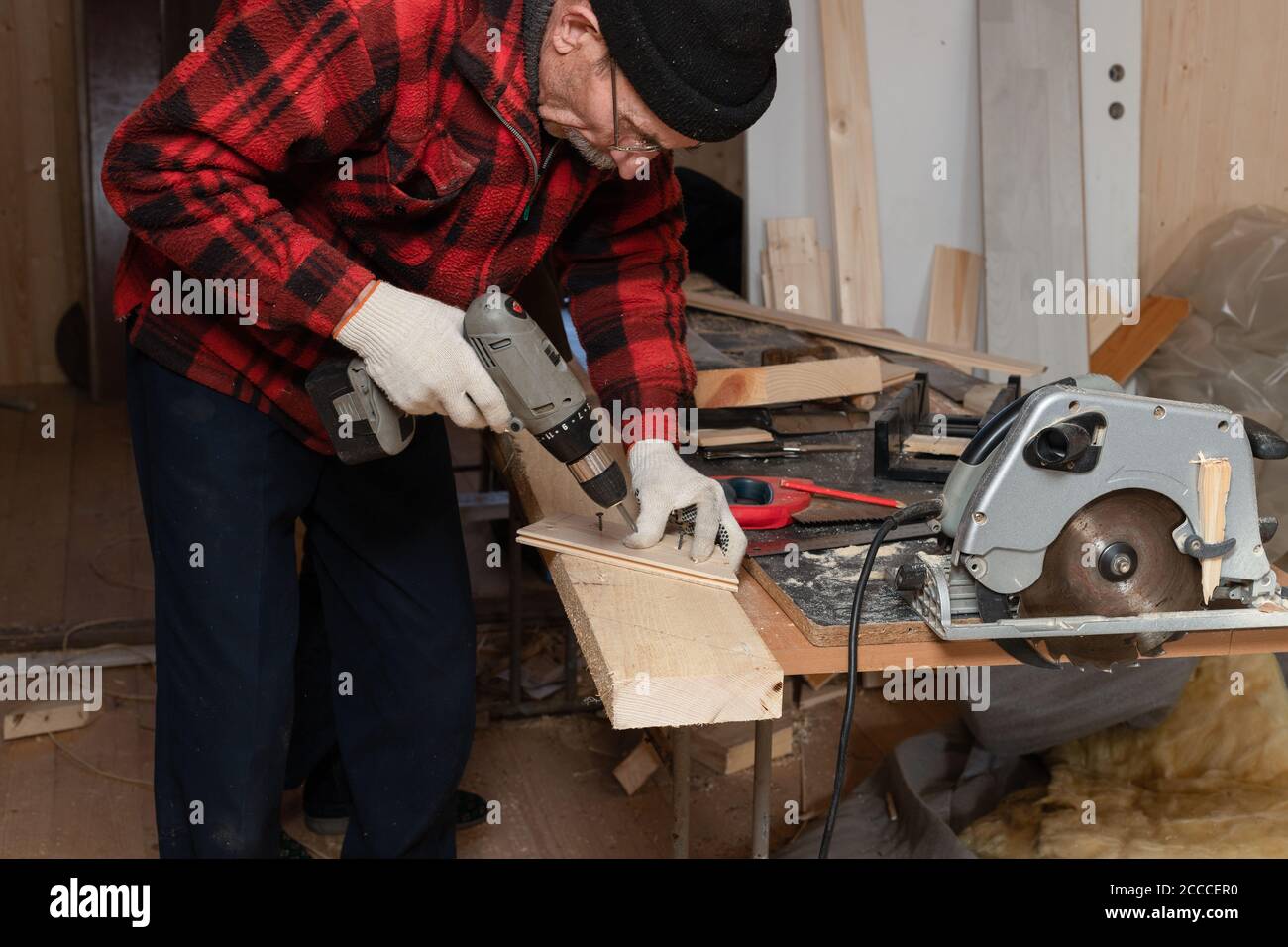 Der ältere Mann arbeitet als Zimmermann in der Werkstatt. Aktives Alter Stockfoto