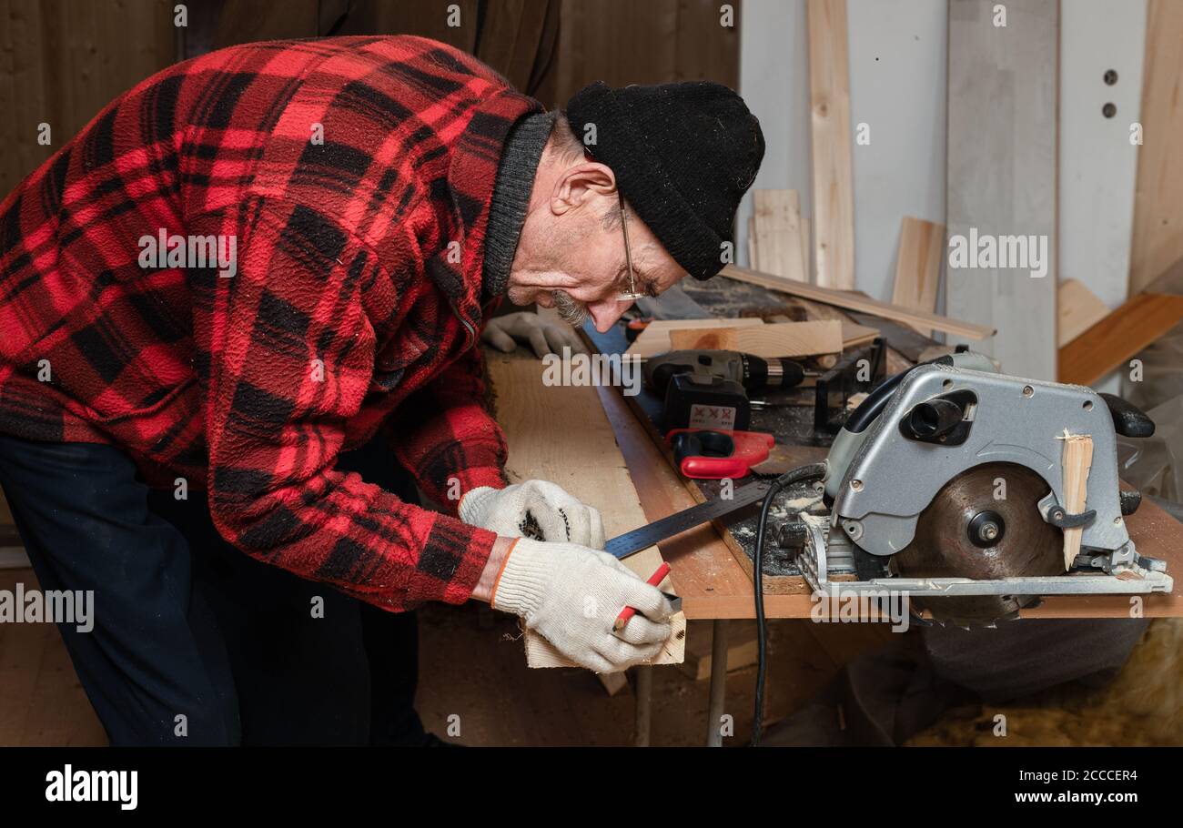 Der ältere Mann arbeitet als Zimmermann in seiner Werkstatt. Aktives Alter Stockfoto