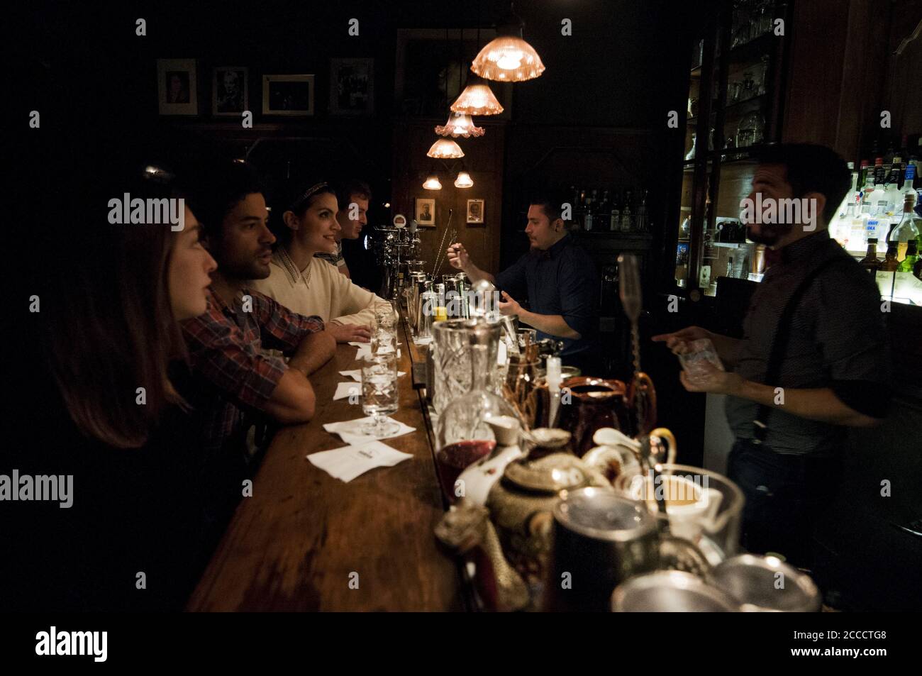 BUENOS AIRES, ARGENTINIEN - 19. Sep 2015: Eine Gruppe junger Leute sitzt an der Bar eines speakeasy Pubs, während die Barkeeper ihre Getränke reparieren. Stockfoto