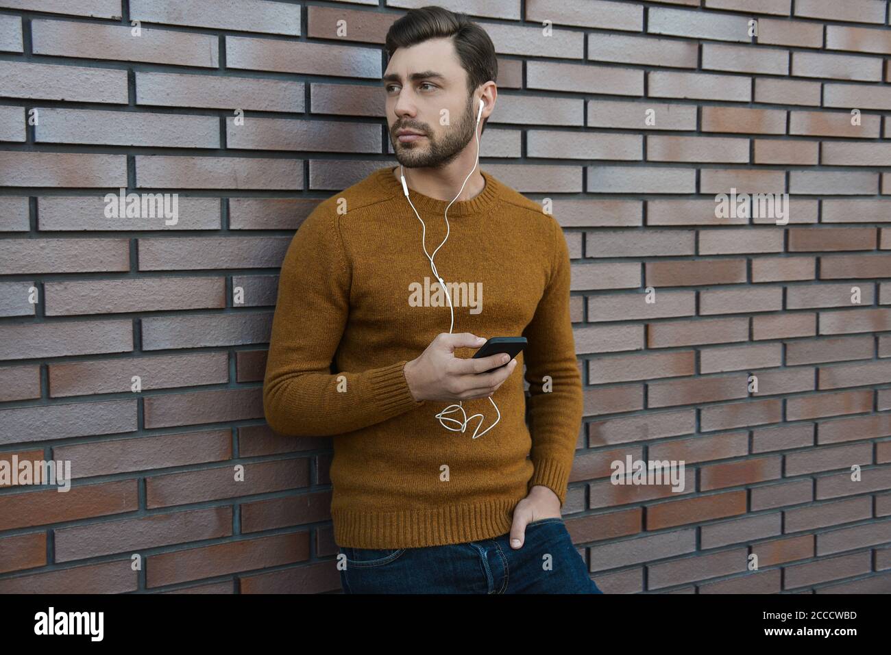 Erstaunlich Mann hält Smartphone in smart Casual wear stehen. Stockfoto