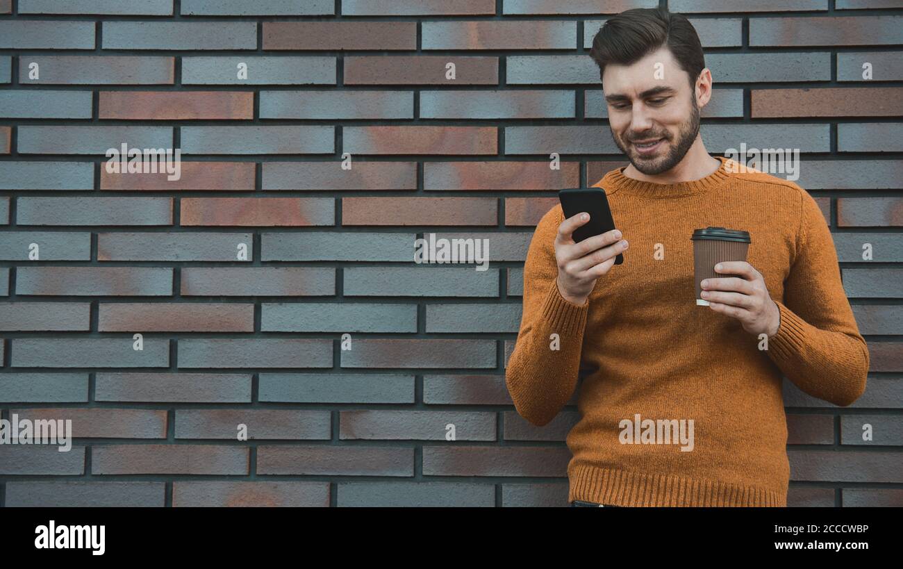 Erstaunlich Mann hält Smartphone in smart Casual wear stehen. Stockfoto