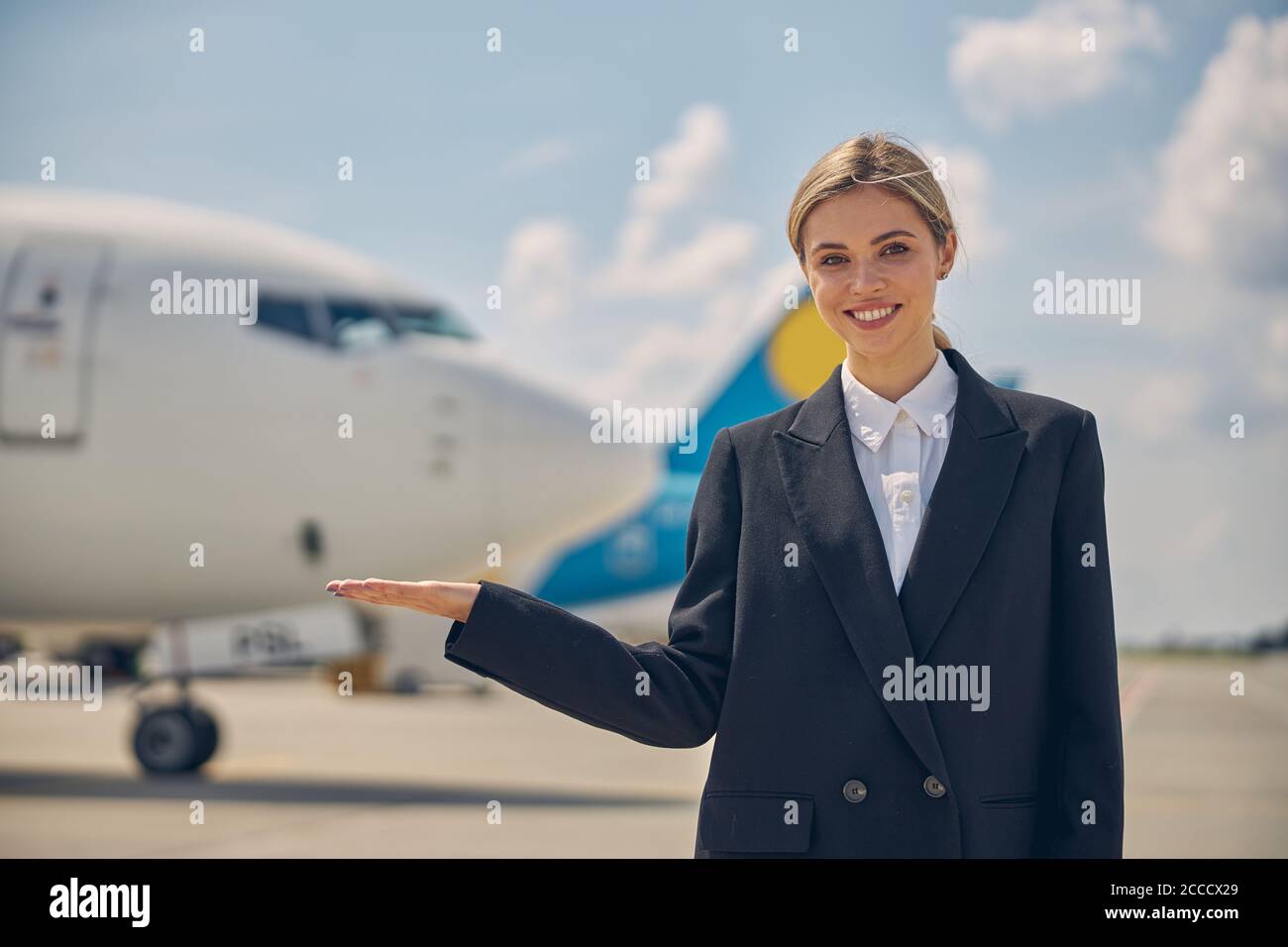 Junge Fluglinienangestellte lächelt an der Kamera Stockfoto