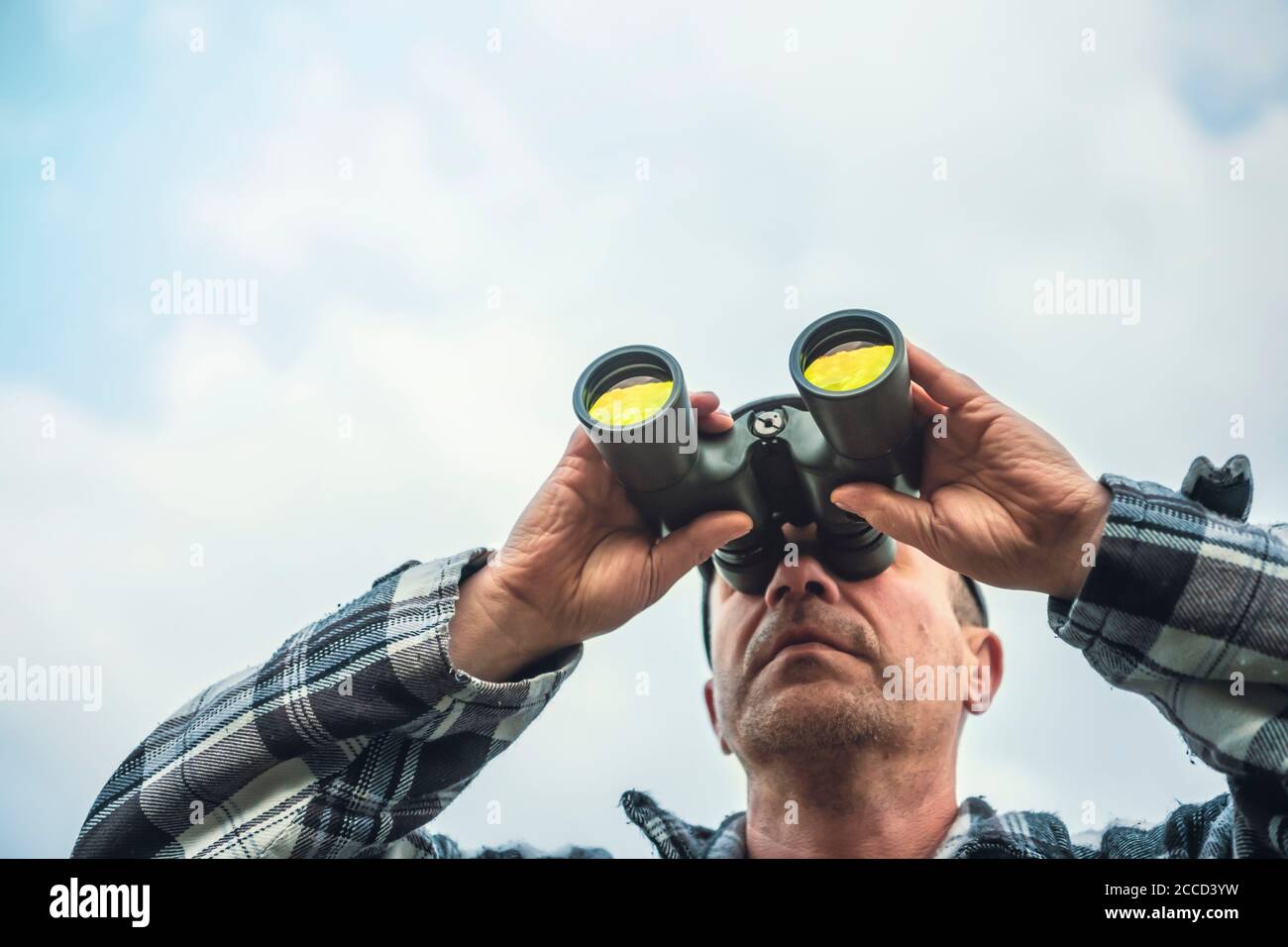 Nahaufnahme eines Mannes, der durch ein Fernglas blickt und dabei kein sichtbares Gesicht hat. Stockfoto