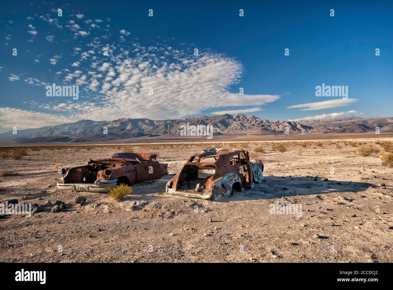 Alte Autowracks, gespickt mit Kugeln, an der Four Mine Road in Panamint Valley, Inyo Mountains in der Ferne, Death Valley National Park, Kalifornien, USA Stockfoto