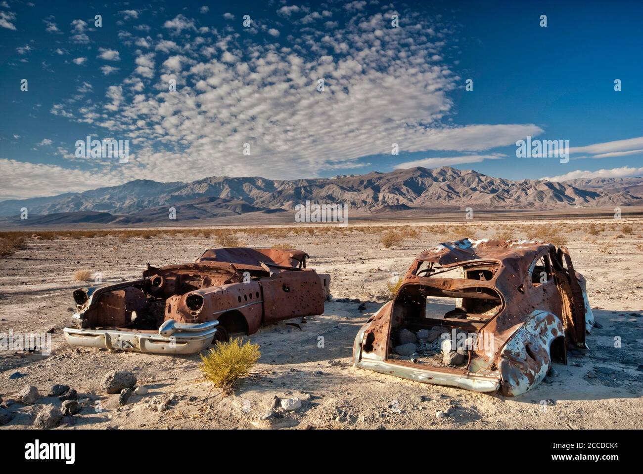 Alte Autowracks, gespickt mit Kugeln, an der Four Mine Road in Panamint Valley, Inyo Mountains in der Ferne, Death Valley National Park, Kalifornien, USA Stockfoto