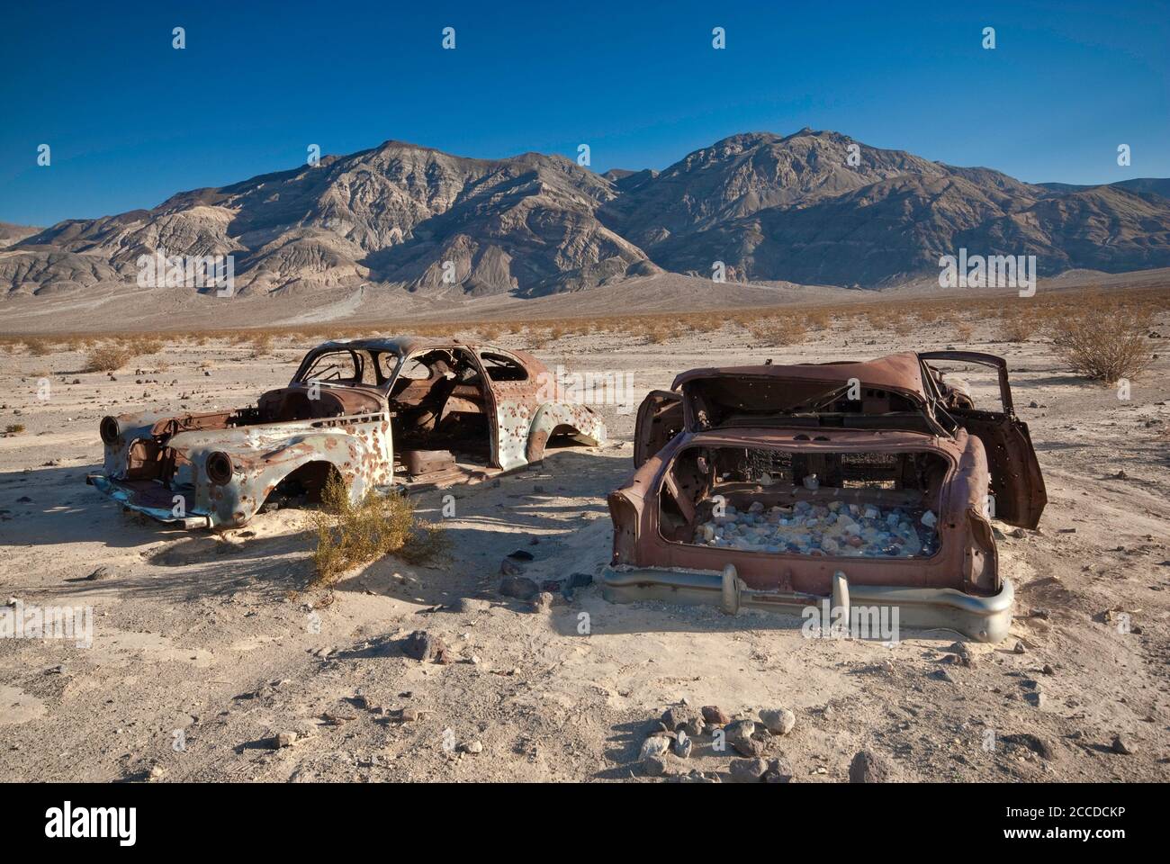 Alte Autowracks, gespickt mit Kugeln, an der Four Mine Road in Panamint Valley, Inyo Mountains in der Ferne, Death Valley National Park, Kalifornien, USA Stockfoto