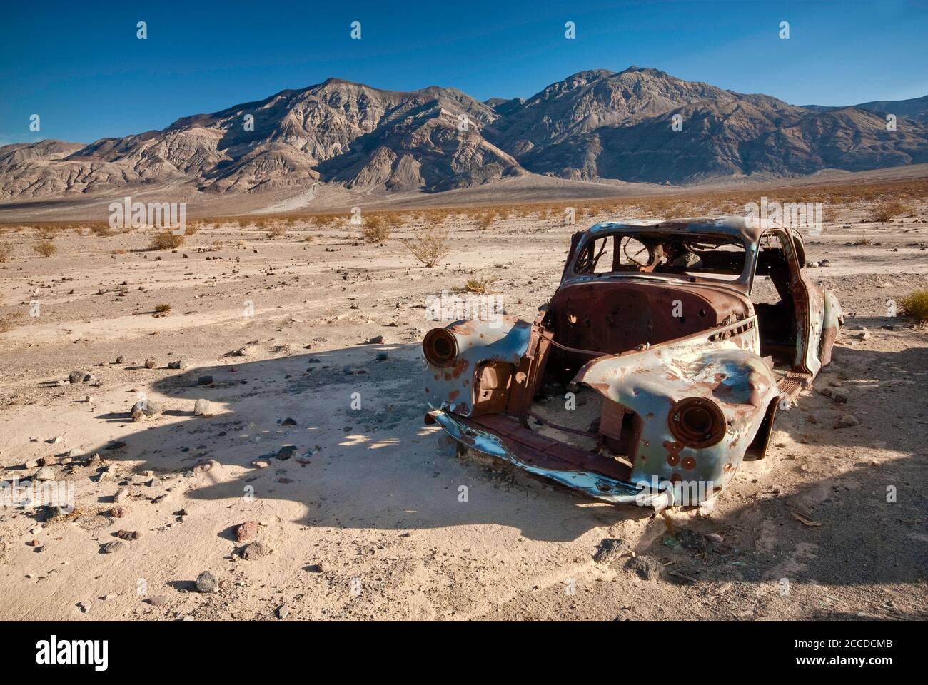 Altes Autowrack, gespickt mit Kugeln, an der Four Mine Road im Panamint Valley, Inyo Mountains in der Ferne, Death Valley National Park, Kalifornien, USA Stockfoto