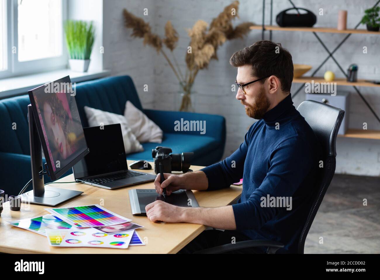 Retusche Bilder in speziellen Programm.Portrait von Grafikdesigner arbeiten im Büro mit Laptop, Monitor, Grafik Zeichnung Tablette und Farbpalette Stockfoto