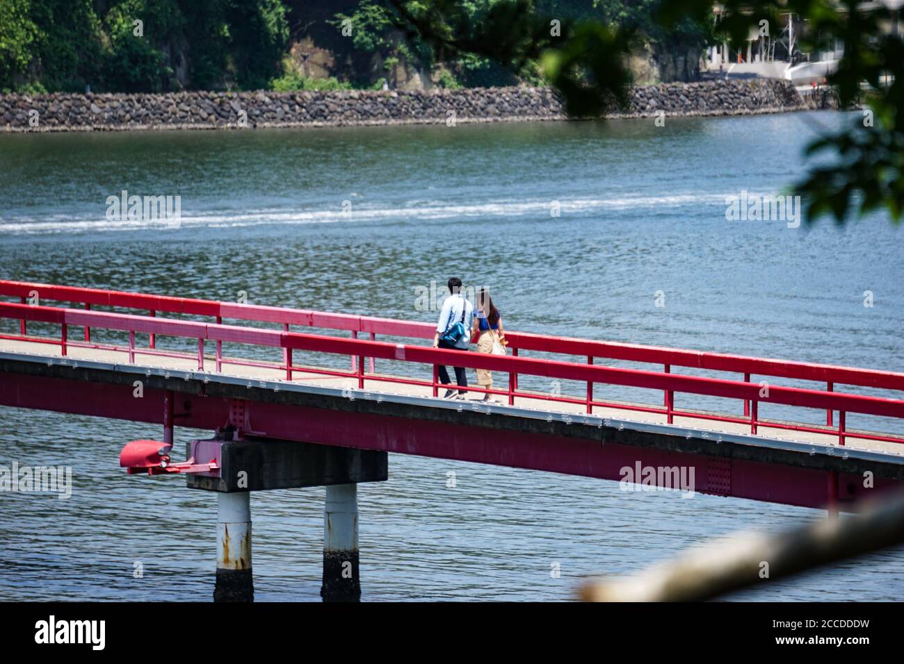 Ein Paar, das in der Ferne über eine rote Brücke ging Stockfoto