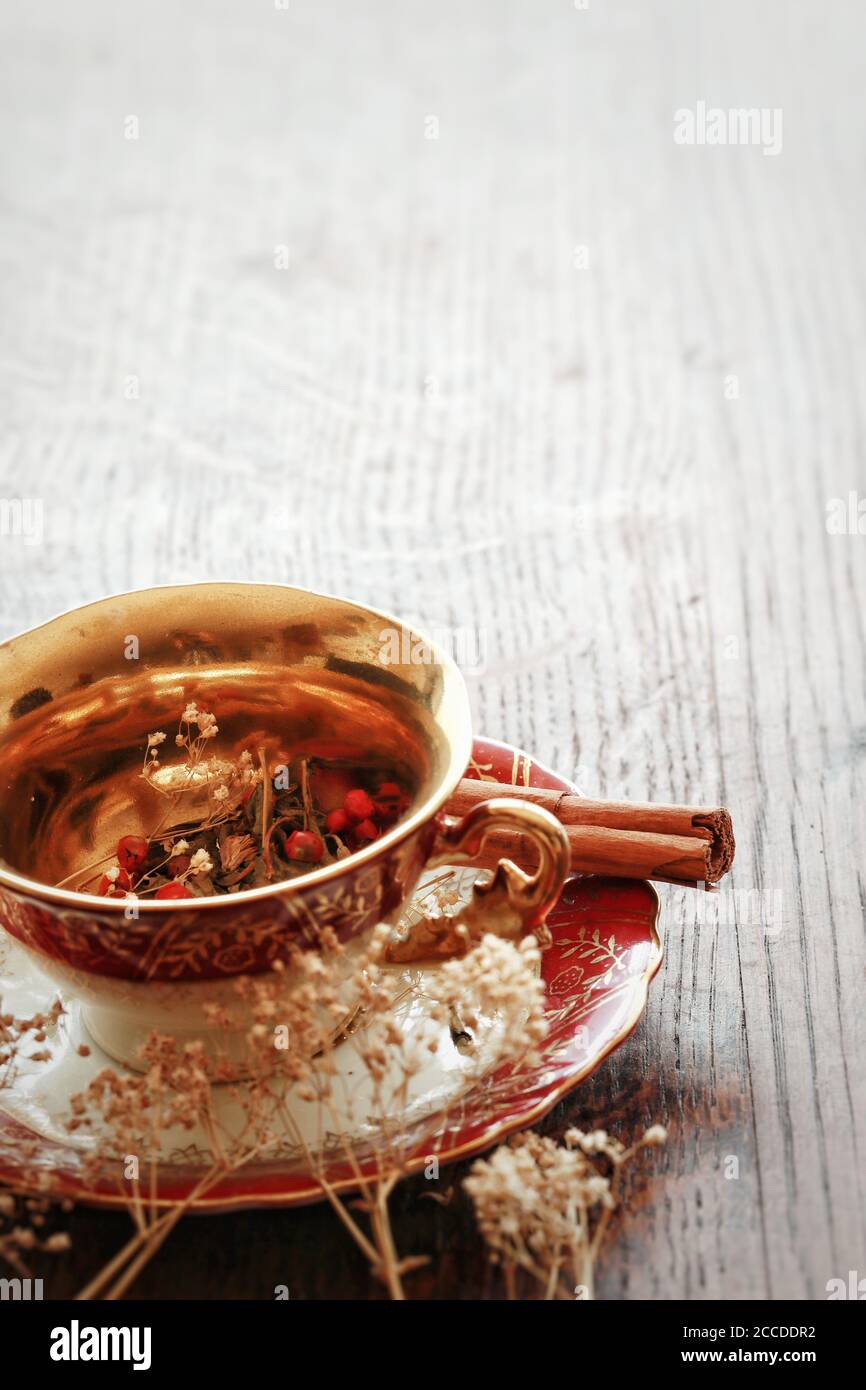 Vertikales Bild von Vintage rot und Gold Tee Tasse mit einigen getrockneten Kräutern, Teeblätter in ihm. Geben Sie in der oberen Hälfte des Schreibens Leerzeichen frei Stockfoto