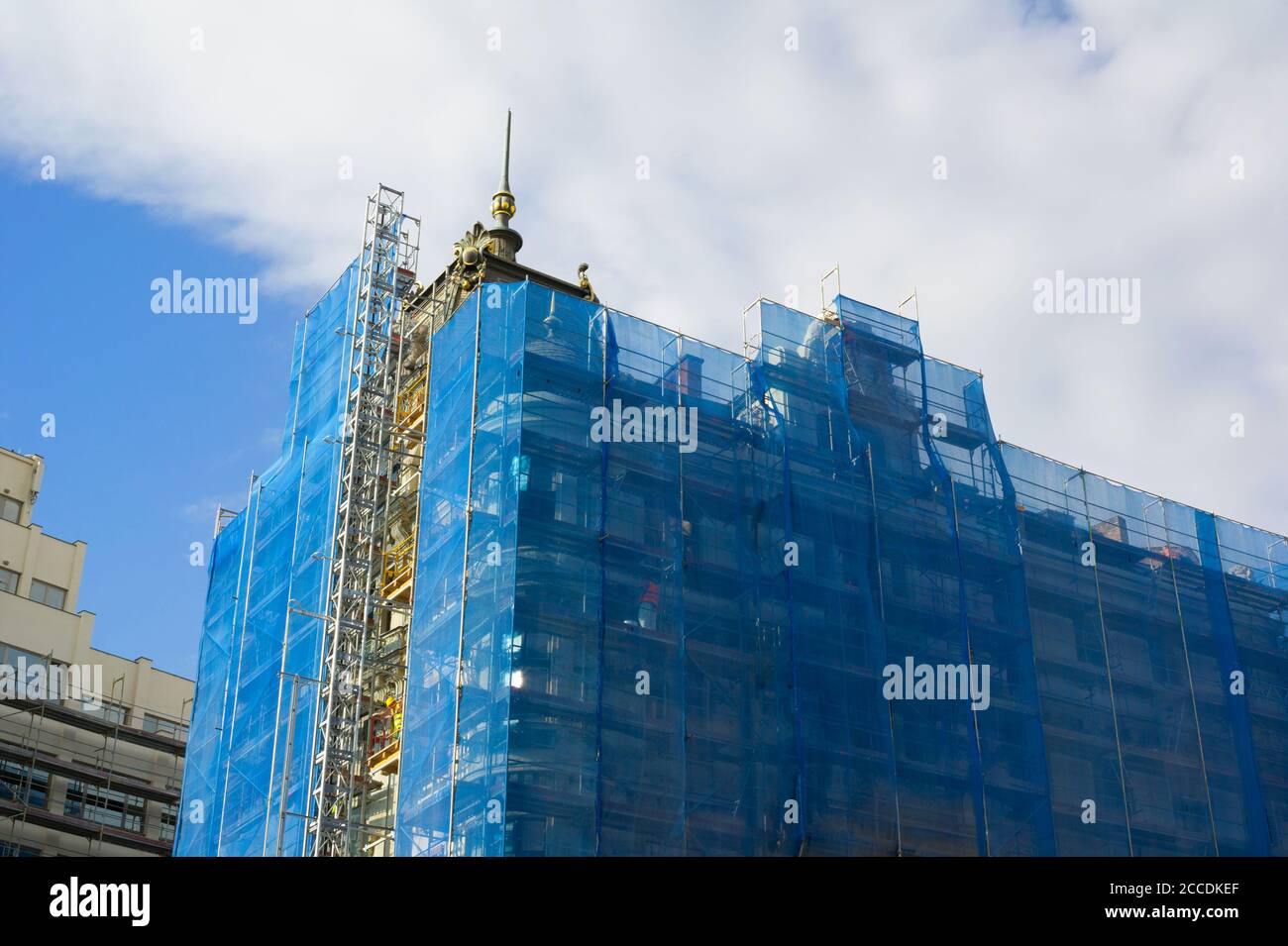 Bau und Rekonstruktion eines mehrstöckigen historischen Gebäudes. Gerüst ist versteckt und bedeckt von coloful blauen Leinwand / Bau Sicherheitsnetz Stockfoto