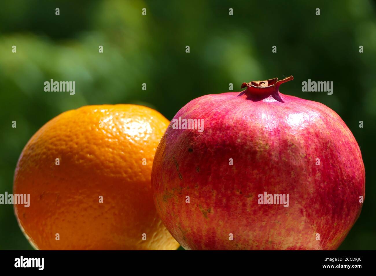 Nahaufnahme Granatapfel und Orange mit grünem Hintergrund Stockfoto
