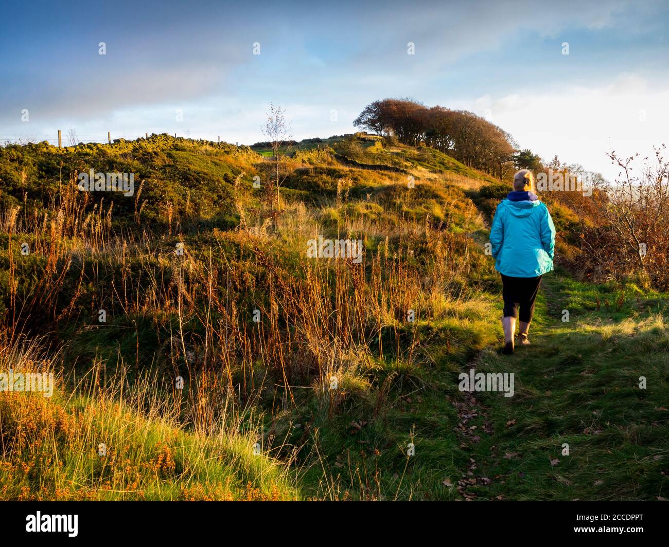 Frau, die in der Herbstlandschaft auf einem Hügel über Starkholmes spazierend ist In der Nähe von Matlock im Derbyshire Peak District England Stockfoto