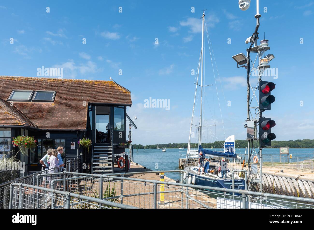 Eingang zur Chichester Marina über das Schleuse- und Kontrollzentrum, Chichester Harbour, West Sussex, UK - eine Yacht, die am Kontrollgebäude vorbeisegelt Stockfoto