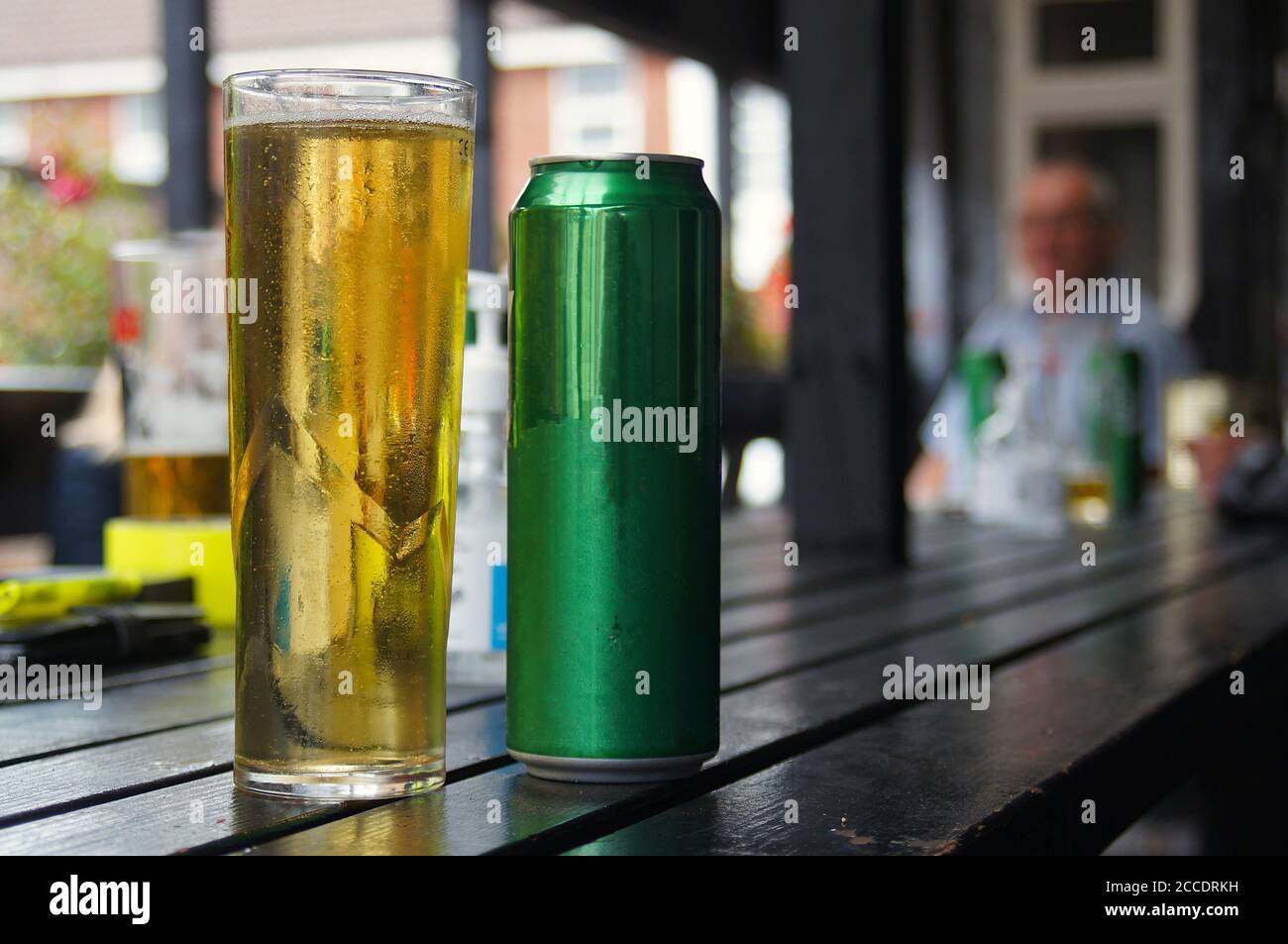 Ein Glas Bier ohne Markenaufdruck und eine Dose auf einer Tischplatte vor einem Pub Stockfoto