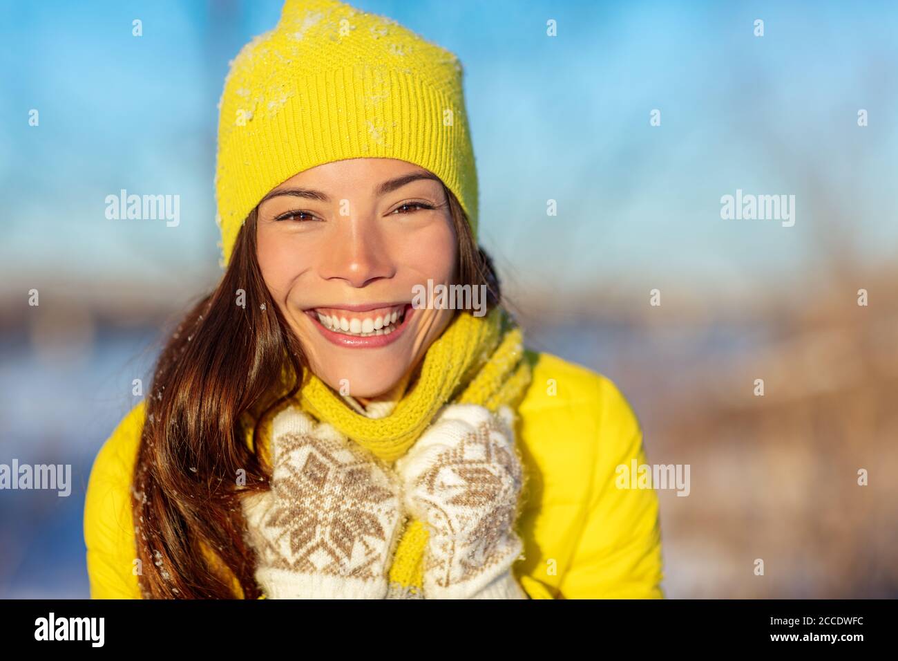 Winter Asian Frau lächelnd bei kaltem Wetter Mode-Accessoires für den Winter: Gelbe Mütze und Strickschal, Wollhandschuhe, Daunenjacke. Glückliches Mädchen genießen Stockfoto