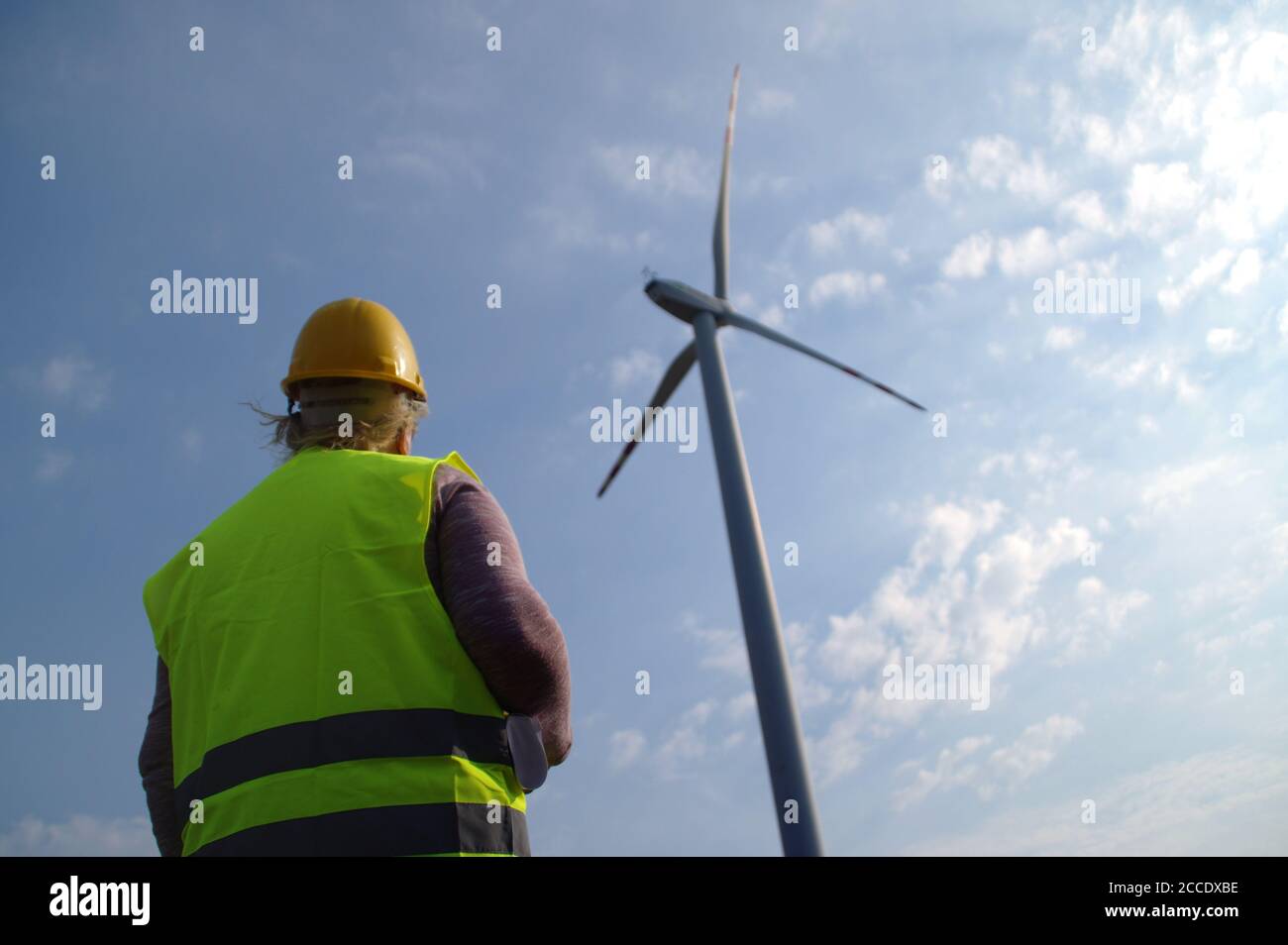 Ingenieur in einer Windenergieanlage. Eine Frau in einem Helm überwacht den Betrieb der elektrischen Windmühlen. Konzept für Ökologie und erneuerbare Energiequellen. Stockfoto