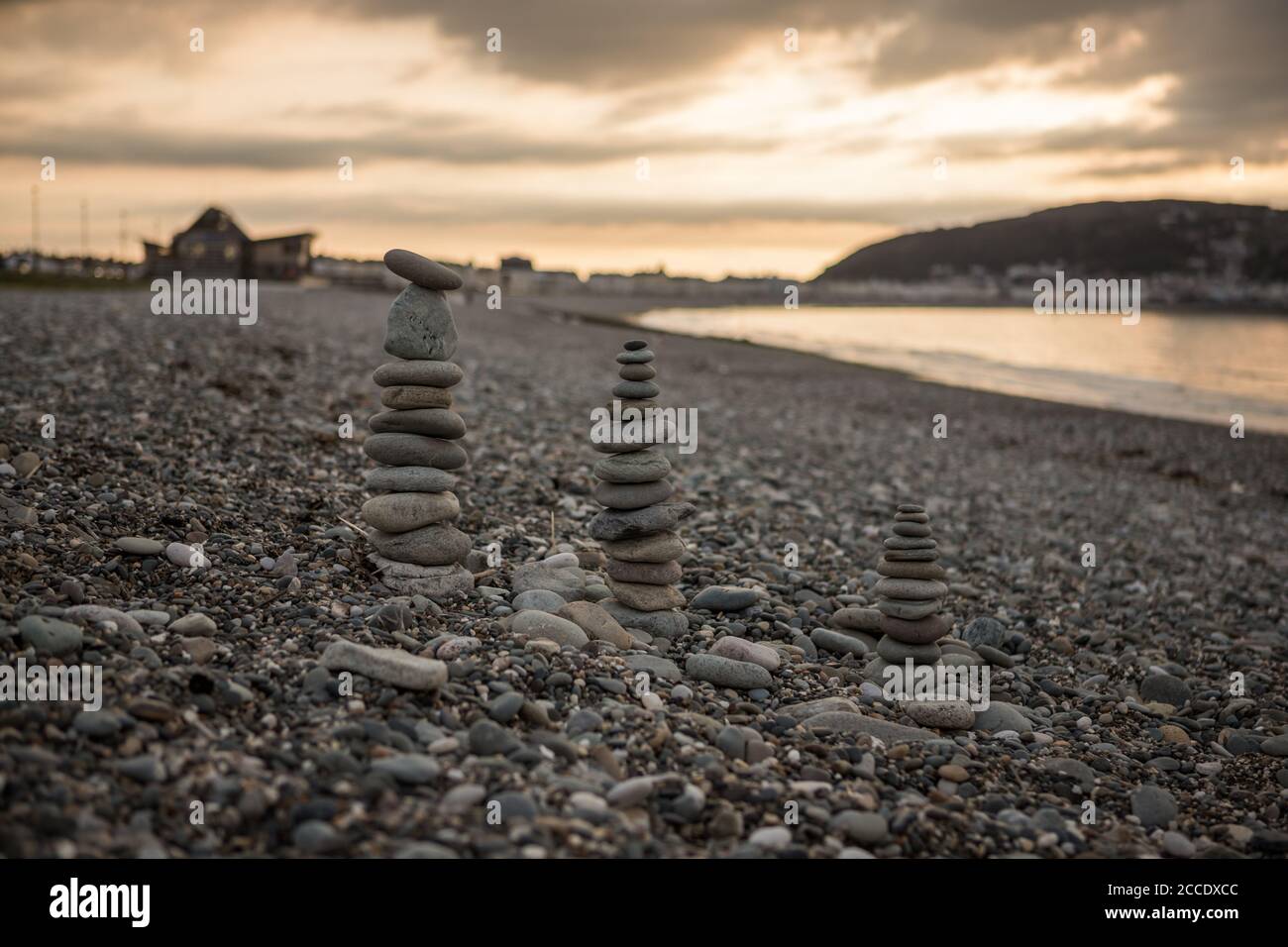 Balancieren von Kieselsteinen an einem felsigen Strand in Nord-Wales. Abend auf Llandudno Kiesstrand Stockfoto