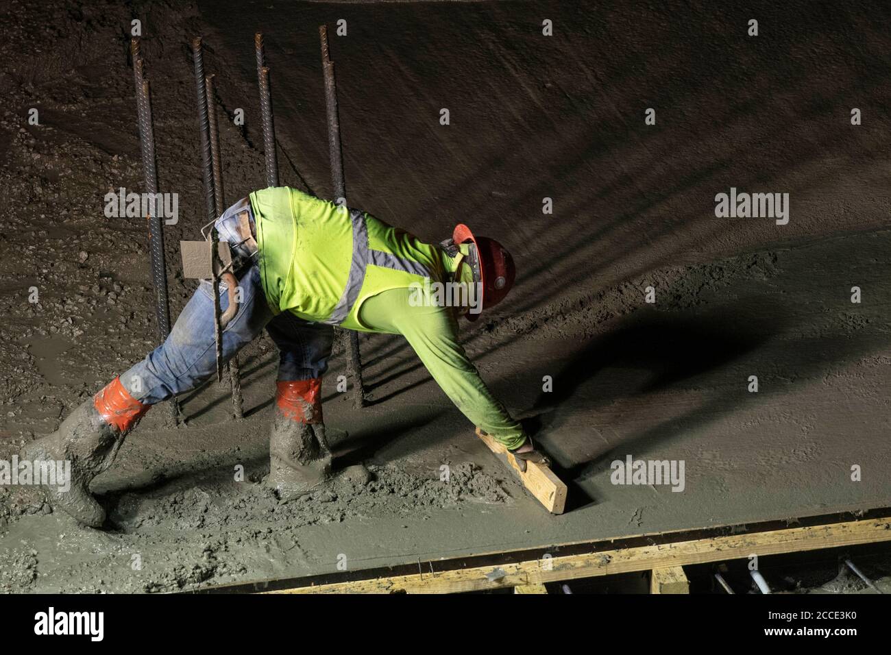 Austin, TX USA 25. Juli 2020: Betonarbeiter nutzt bei einem nächtlichen Pausenausbruch in der Innenstadt von Austin, TX, Beton auf dem Parkgaragenboden eines 53-stöckigen Gebäudes. Trotz der landesweiten COVID-19-Pandemie und des Staates, der mit über einer halben Million Fällen und über 10,000 Todesfällen heimgesucht wird, werden in Texas weiterhin riesige Bauprojekte unvermindert durchgeführt. Stockfoto