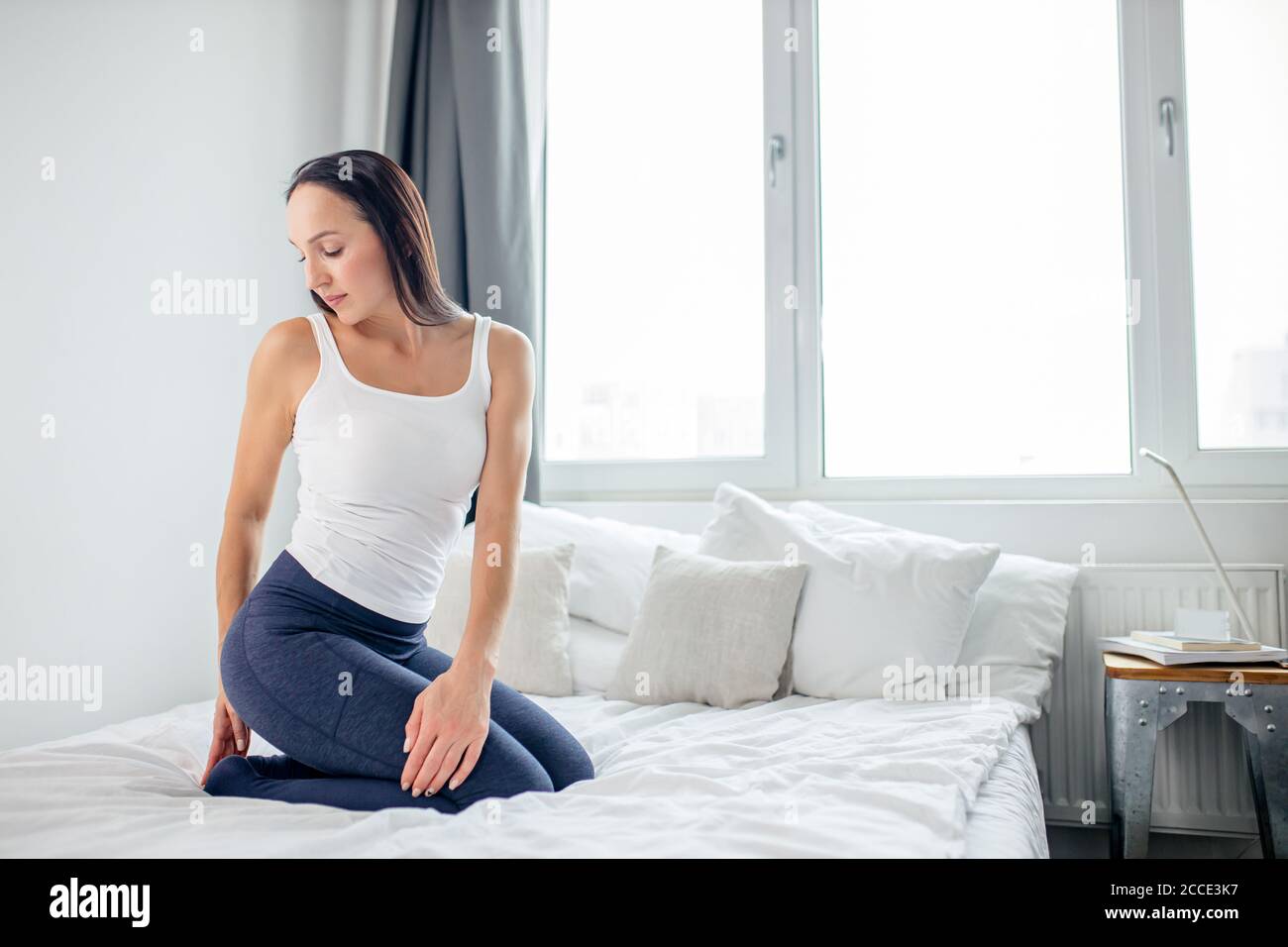 Gut aussehende kaukasische Frau Stretch Hals und ganzen Körper auf dem Bett zu Hause, am Morgen Stockfoto