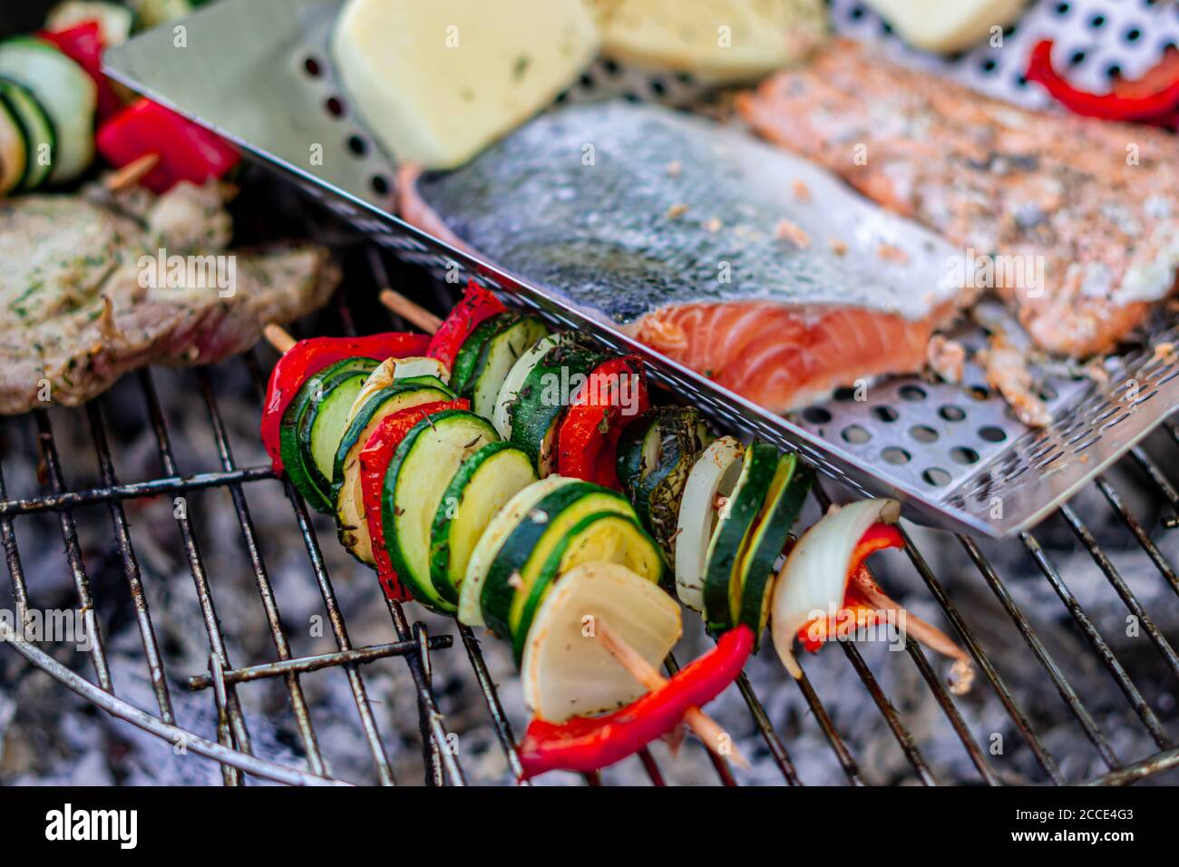 Grillen von Gemüsespießen und Fisch Stockfoto