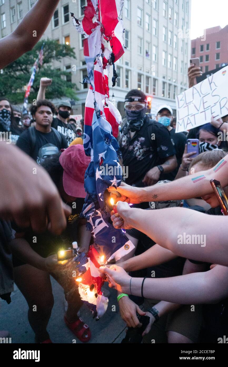 Tulsa, OK, USA. 20. Juni 2020 Demonstranten greifen mit Feuerzeugen aus, um eine amerikanische Flagge zu verbrennen, aus Protest gegen eine Kundgebung von Präsident Donald Trump. Stockfoto