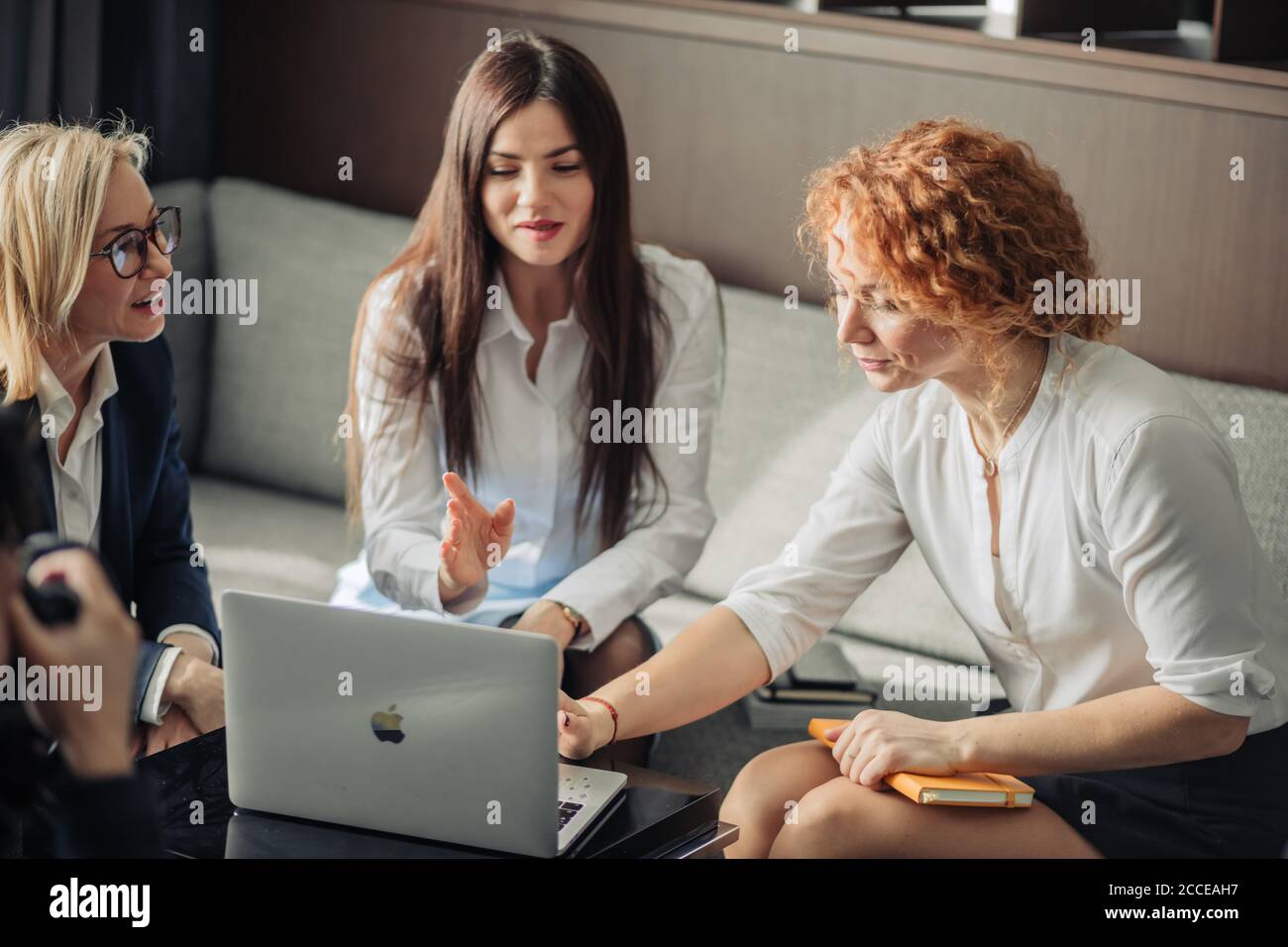 Schöne clever niedlich charmant attraktive elegante weibliche Geschäftspartner haben Online-Treffen mit potenziellen Investor, sammeln im Kreis in der Nähe von Tisch wi Stockfoto