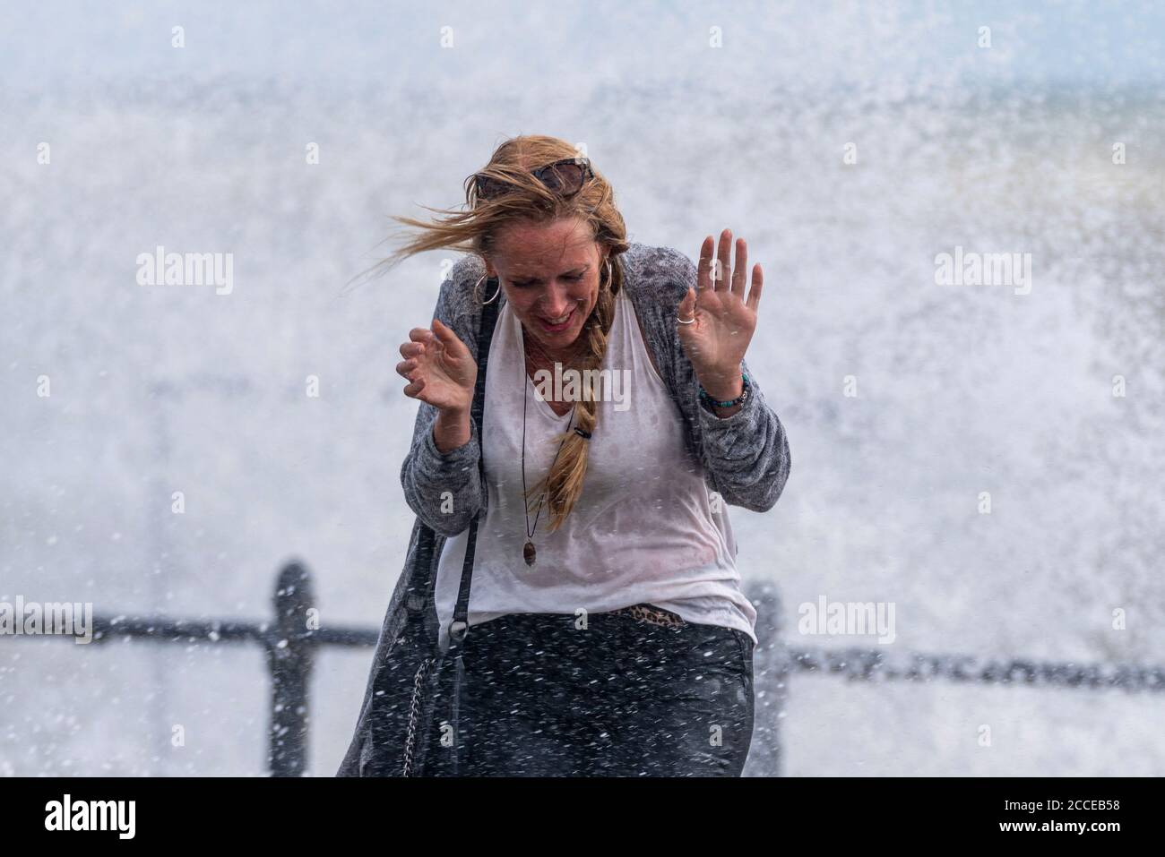 Weiße kaukasische Frau, die während der starken Winde des Sturms Ellen nass wird von den Wellen in Southend on Sea, Essex, Großbritannien. Geschockt vom Spritzwasser Stockfoto