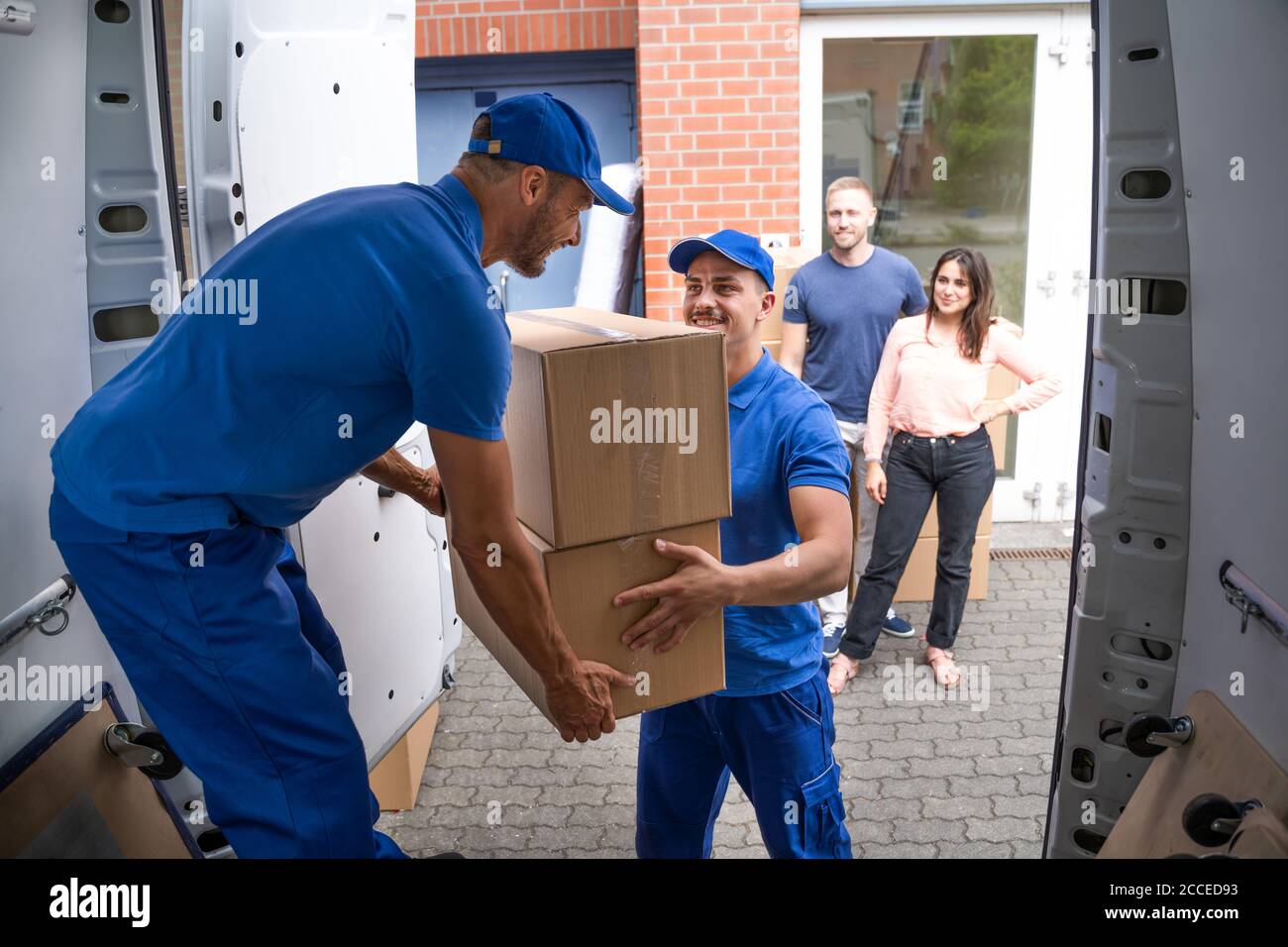 Glückliche Familie Paar Beobachten Movers Entladen Boxen Von Lkw Stockfoto
