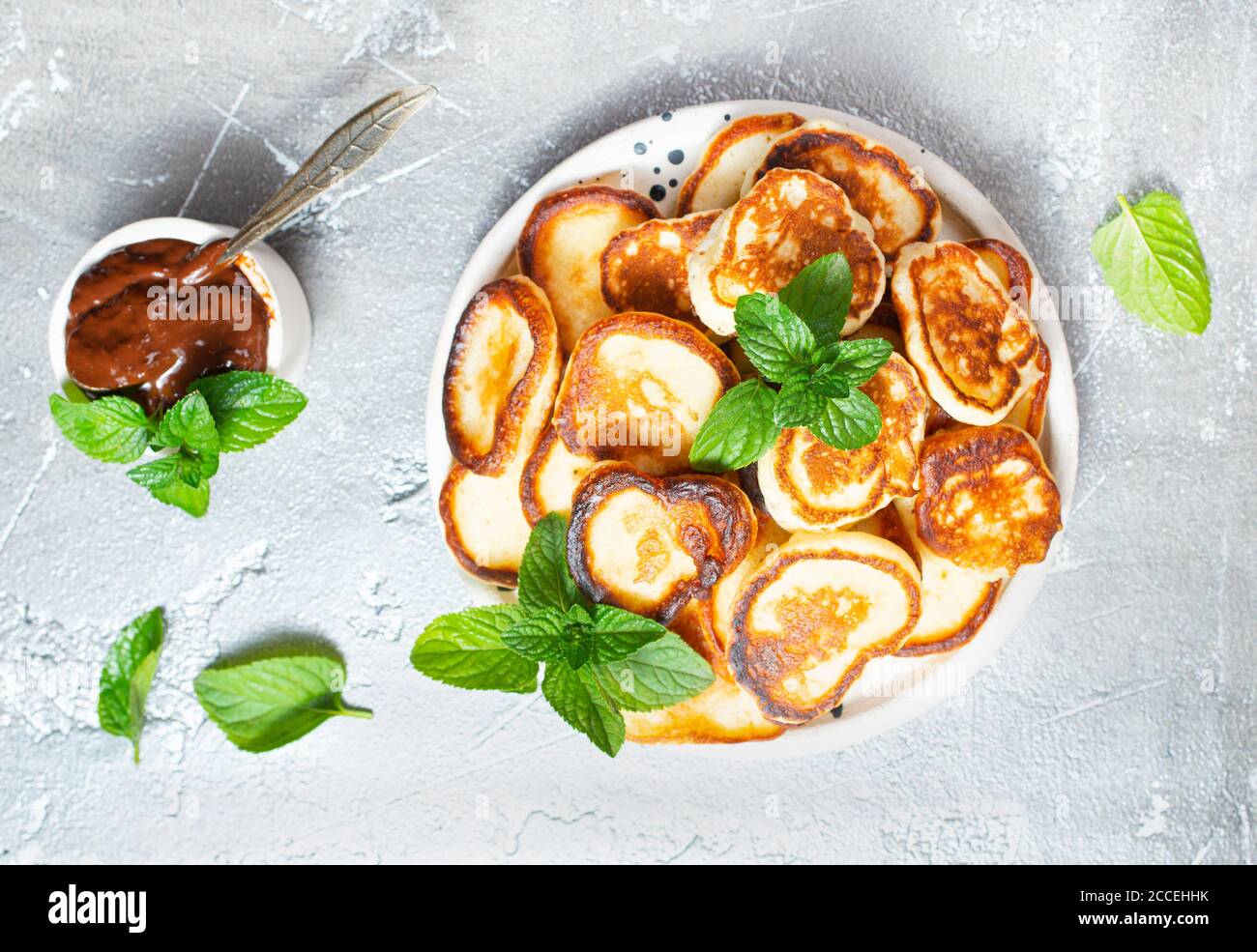 Mini-Pfannkuchen auf dem Teller, Draufsicht Tischszene auf einem grauen Hintergrund. Stockfoto