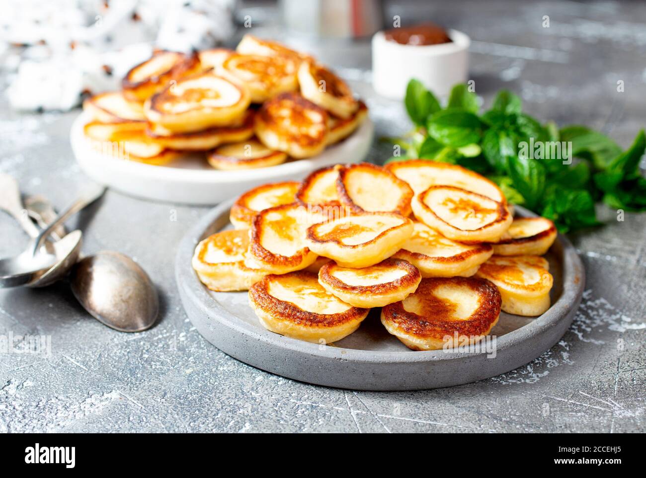 Mini-Pfannkuchen auf dem Teller, Draufsicht Tischszene auf einem grauen Hintergrund. Stockfoto