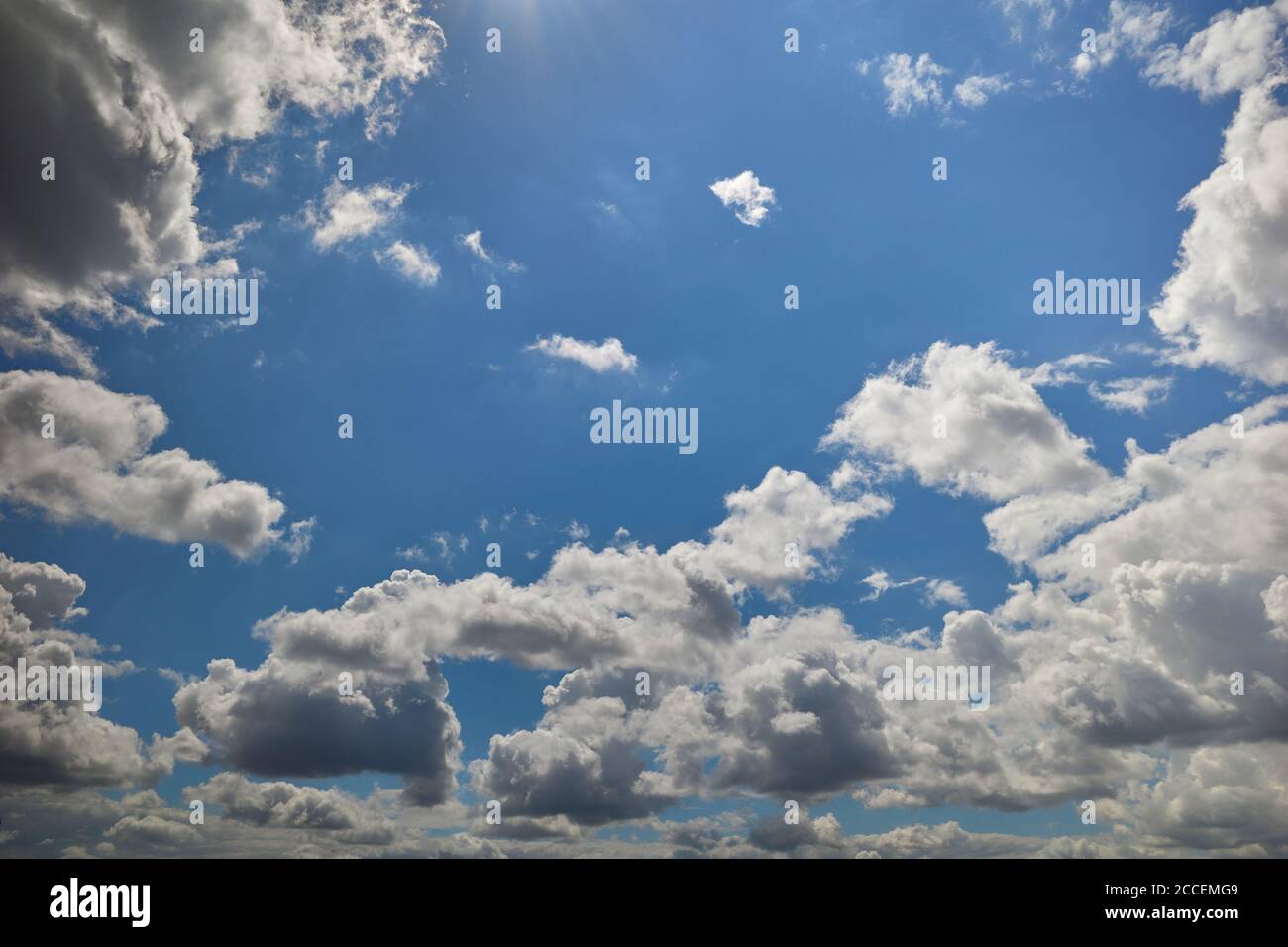 Regenwolken in blauem Himmel durch Sonnenstrahlen aufgehellt. Hintergrund für Vorhersage und Meteorologie Illustration. Cumuli Wolken schweben über dem blauen Himmel Stockfoto