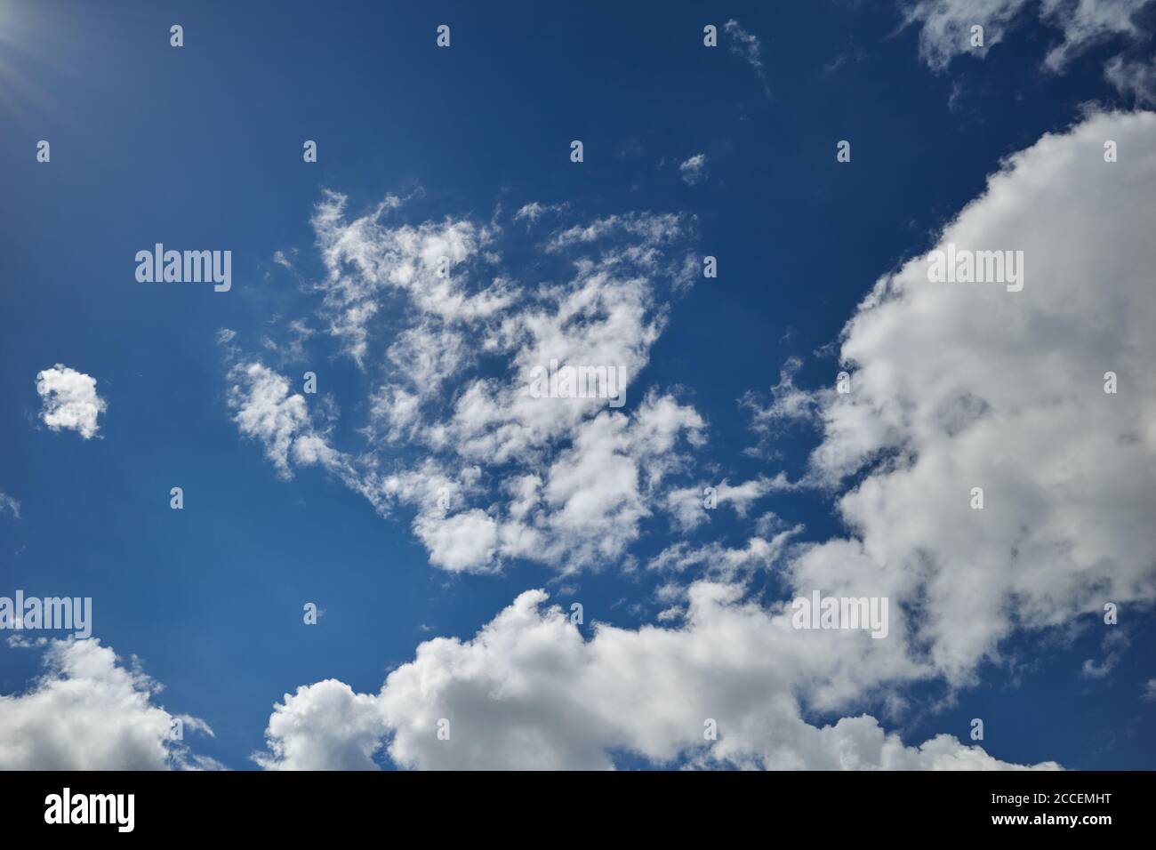 Die Sonnenstrahlen erleuchteten einen blauen Himmel, der mit Kumuluswolken bedeckt war. Hintergrund für Vorhersage und Meteorologie Illustration. Sonneneinstrahlung. Sonnenstrahlen Stockfoto