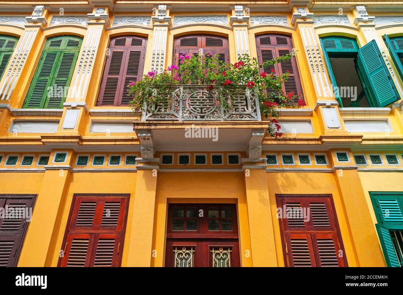 Fassade im französischen Kolonialstil und Balkon mit Blumen und Fenstern, Hanoi City, Nordvietnam. Stockfoto