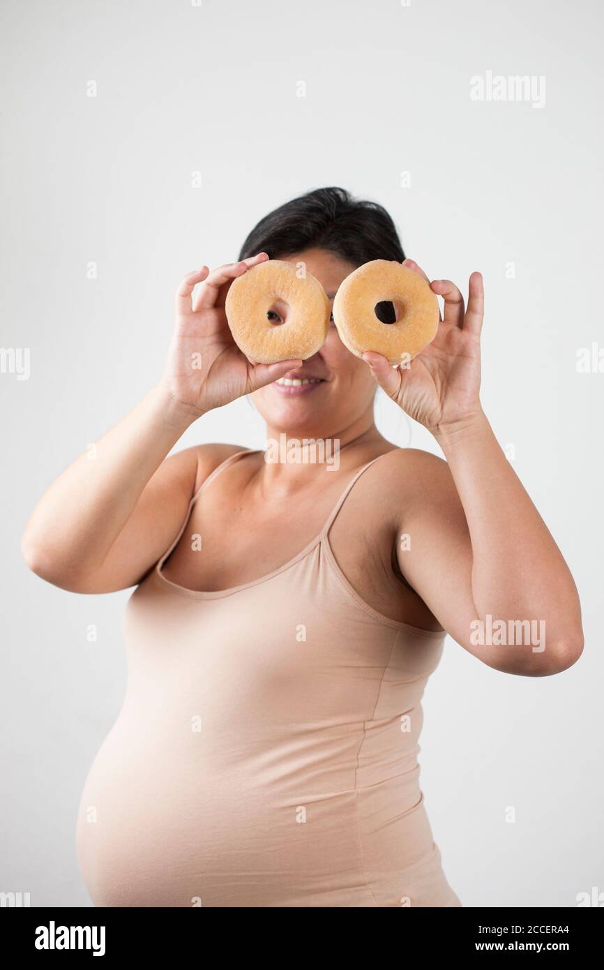 Schwangere Frau hält Donuts Stockfoto