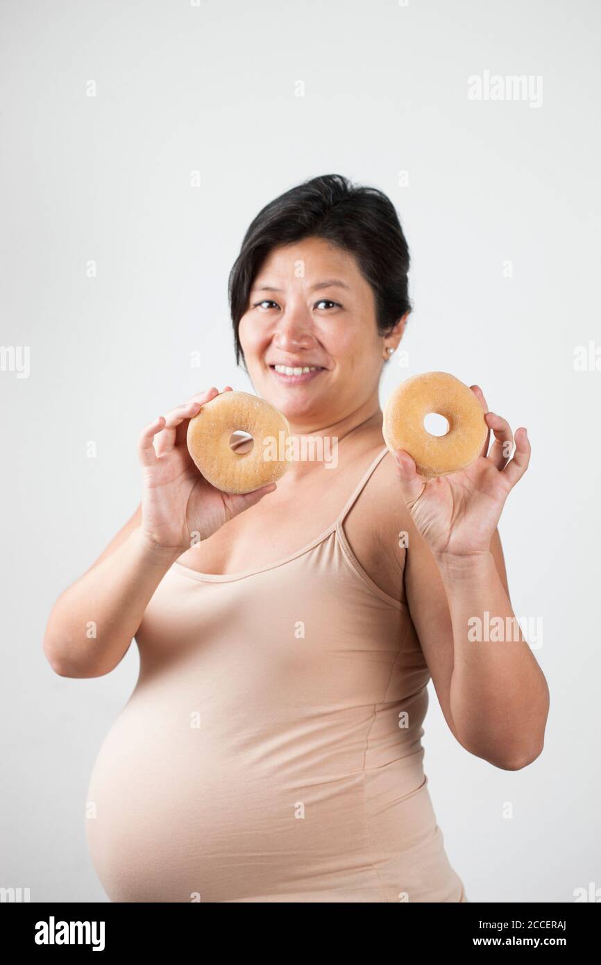Schwangere Frau hält Donuts Stockfoto